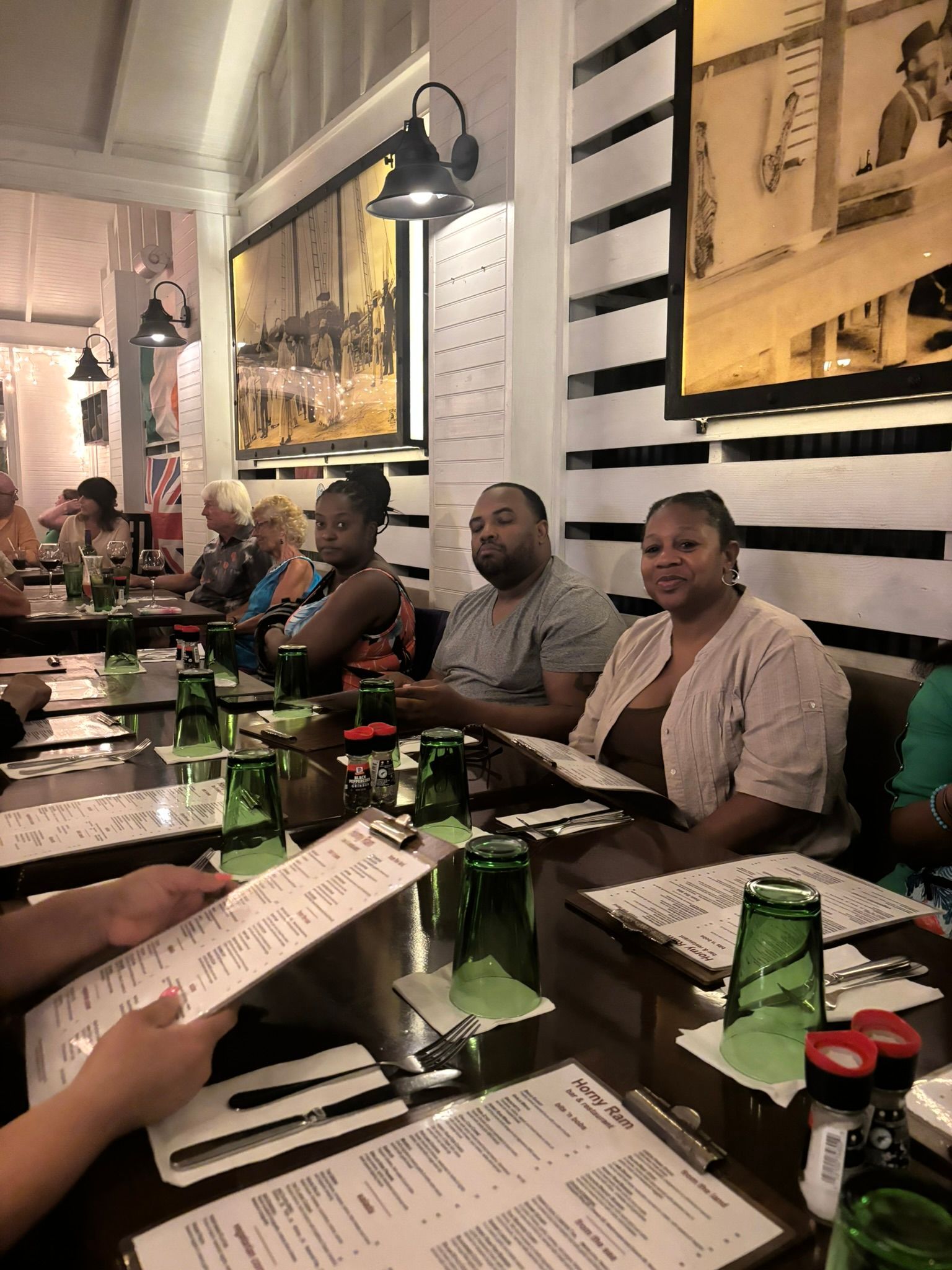 A group of people are sitting at tables in a restaurant looking at menus.