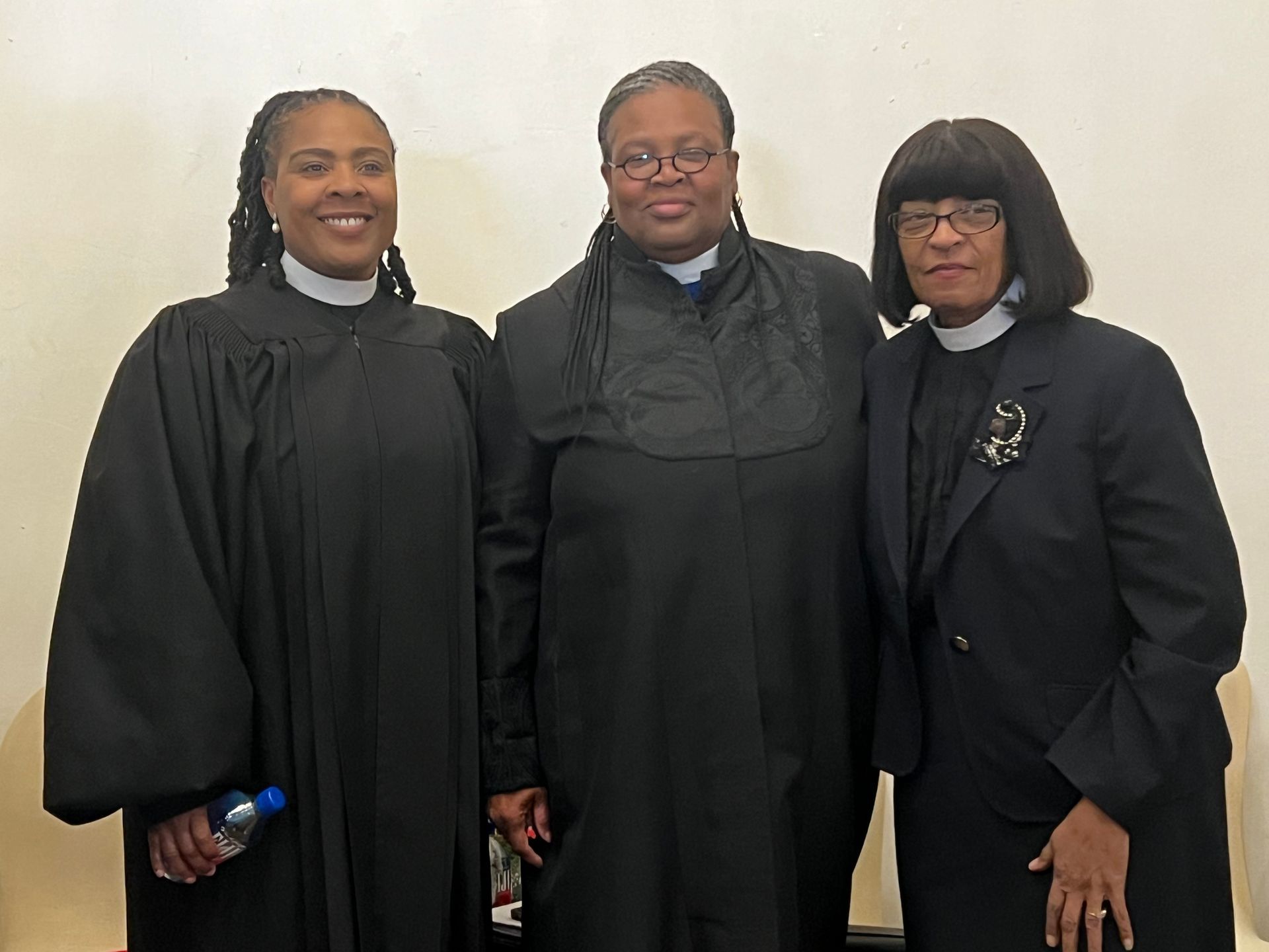 Three women in black gowns are posing for a picture