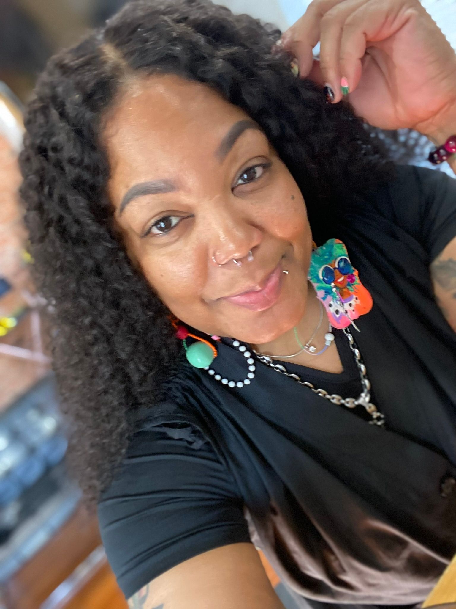 A woman with short hair is smiling in front of a purple wall.