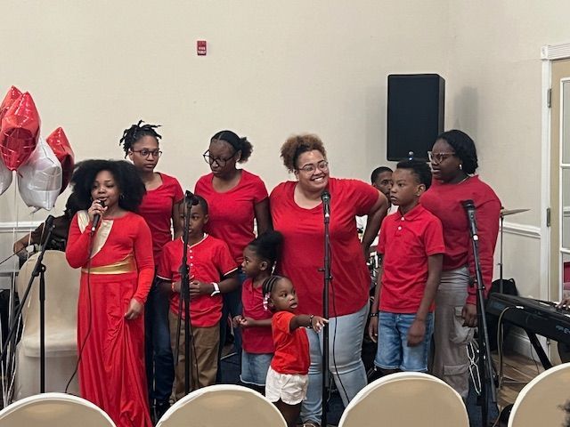 A group of people in red shirts are singing into microphones.