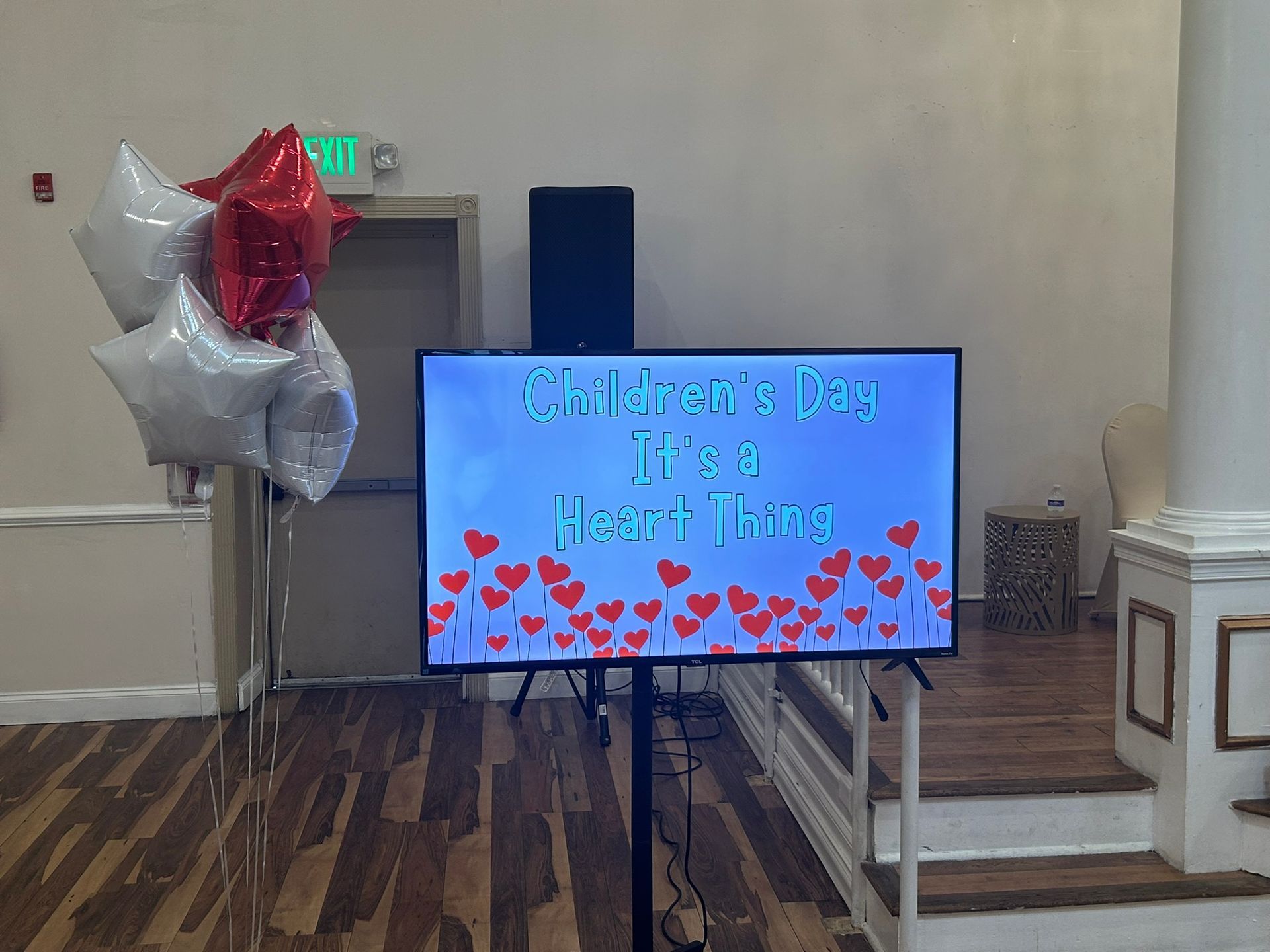 A television is sitting on a stand in a room with balloons.