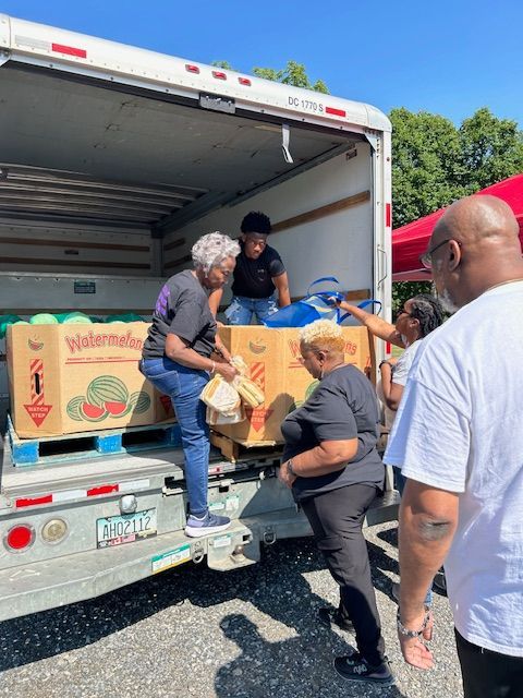 A group of people are loading watermelons into a truck.