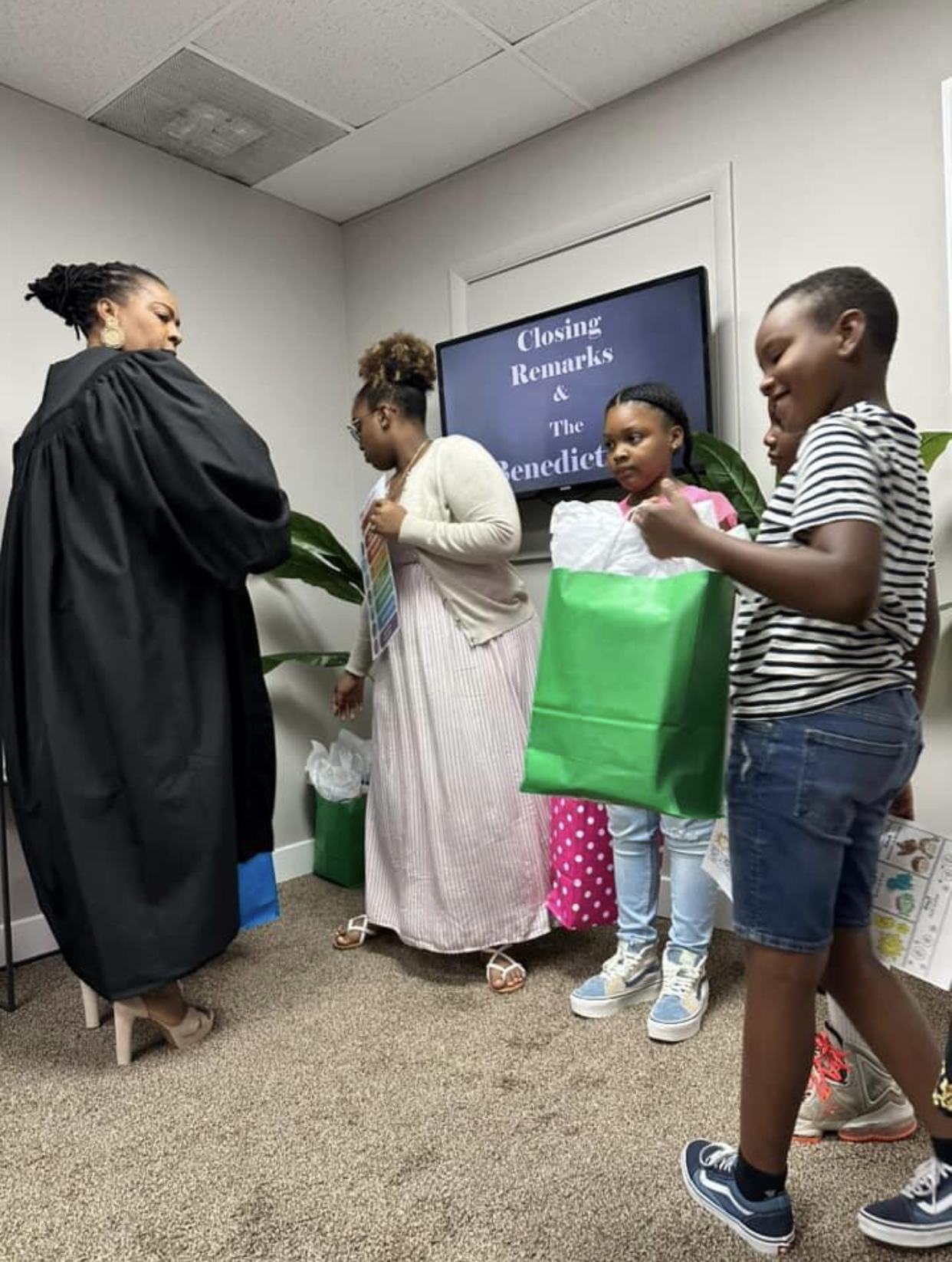 A group of people are standing in a room holding gifts.