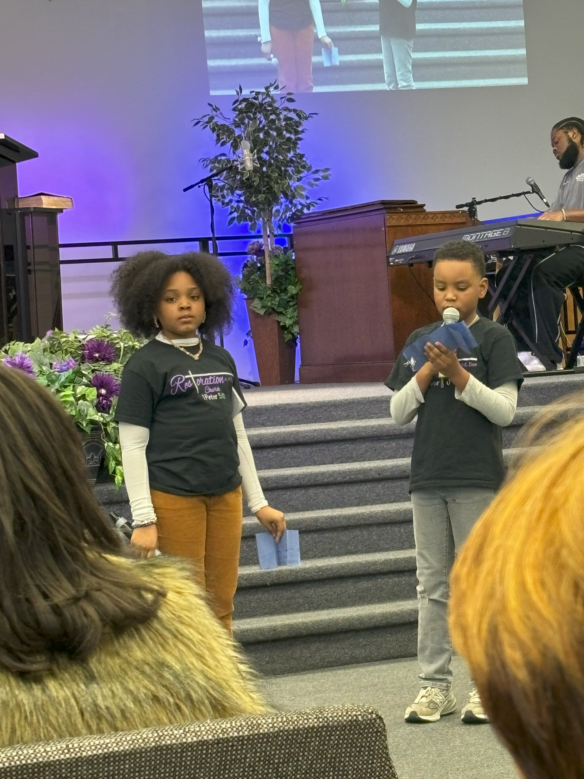 A boy and a girl are giving a presentation in front of a crowd