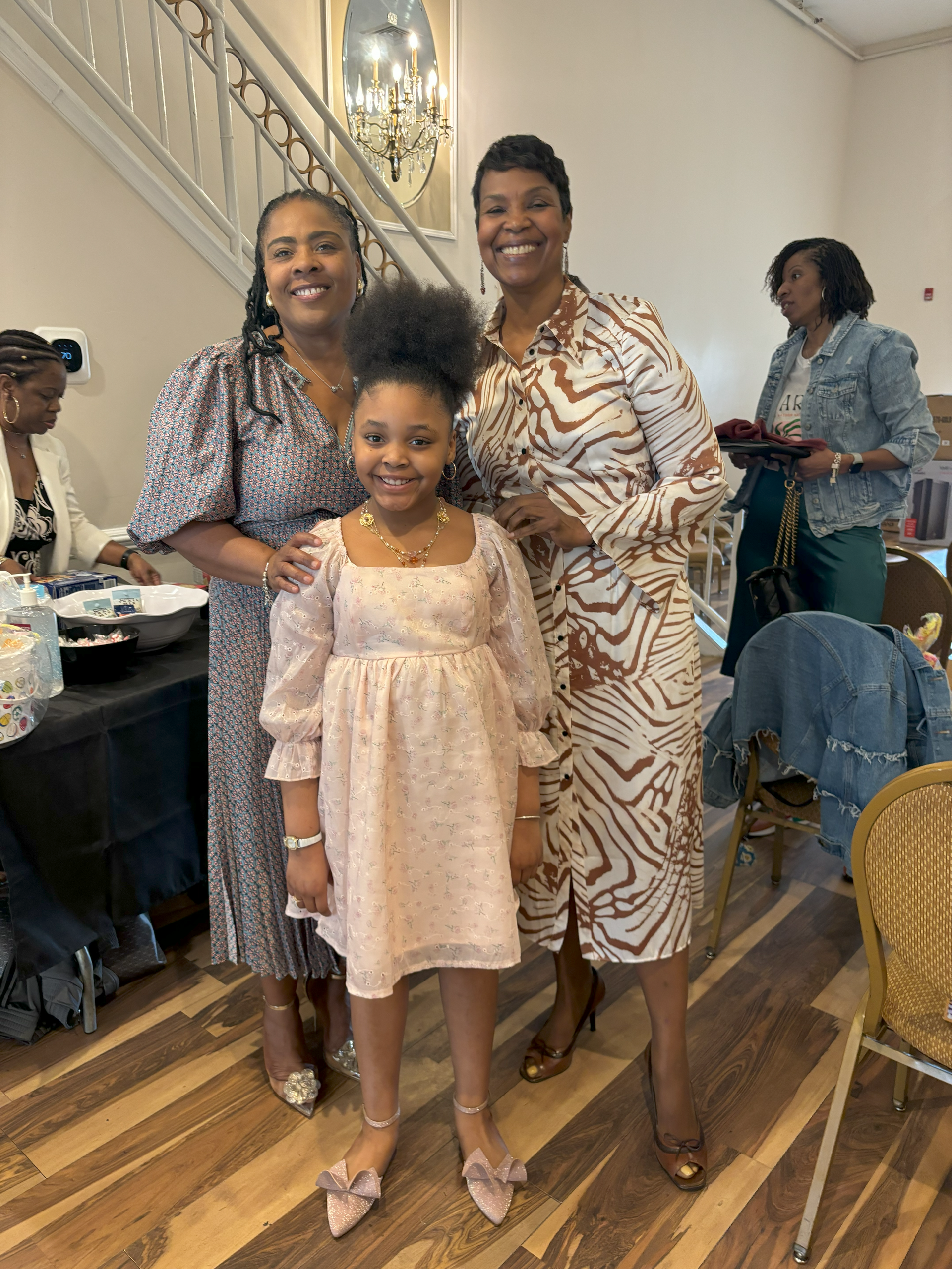 Three women and a little girl are posing for a picture in a room.