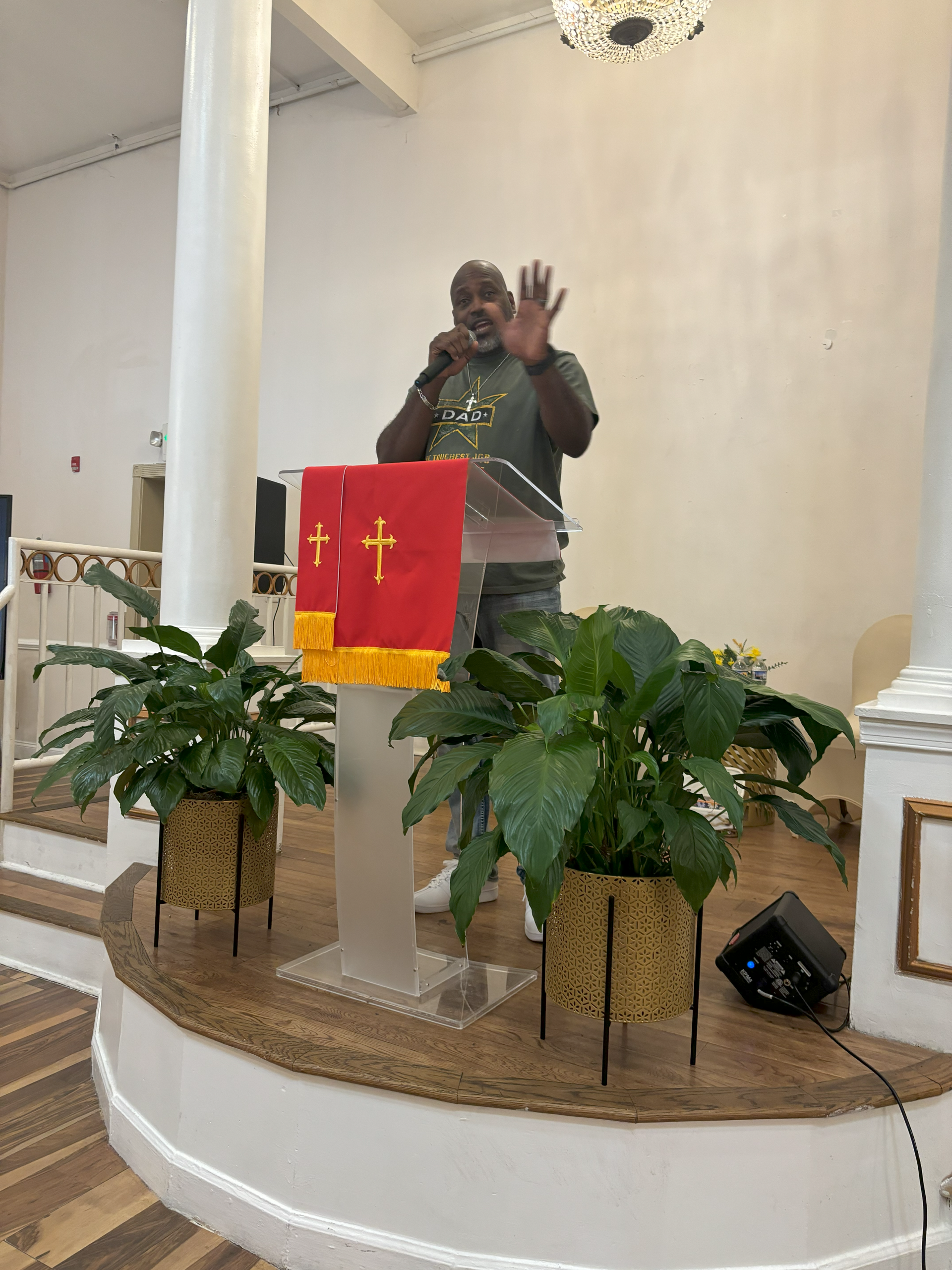 A man is standing at a podium with a red flag with a cross on it.