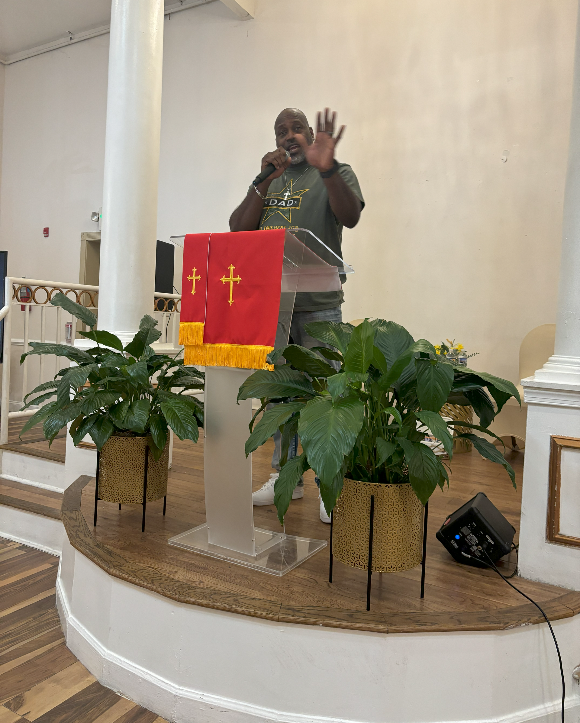 A man is standing at a podium in a church talking into a microphone.