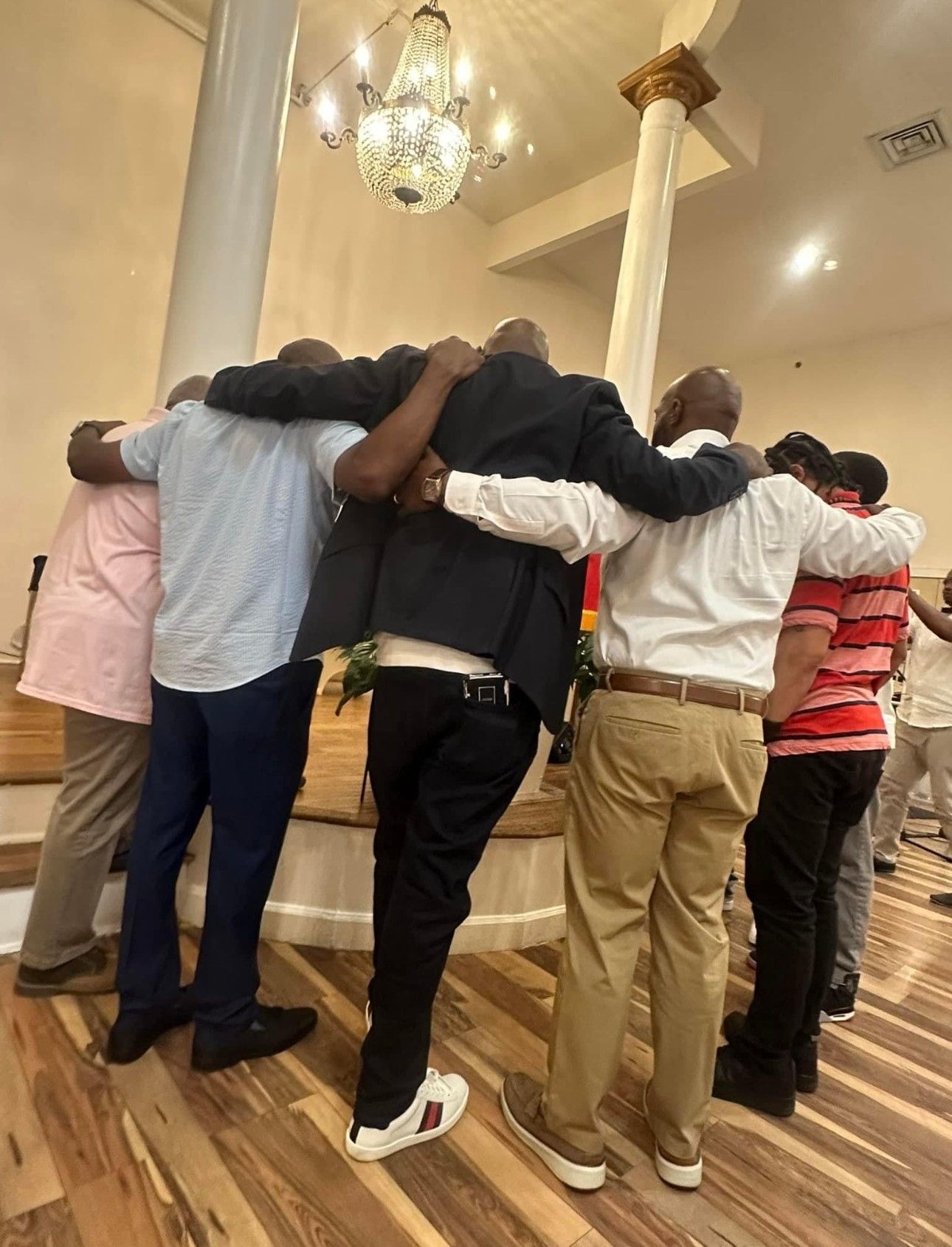 A group of men are hugging each other in a room.