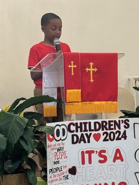 A boy stands at a podium with a sign that says children 's day 2024