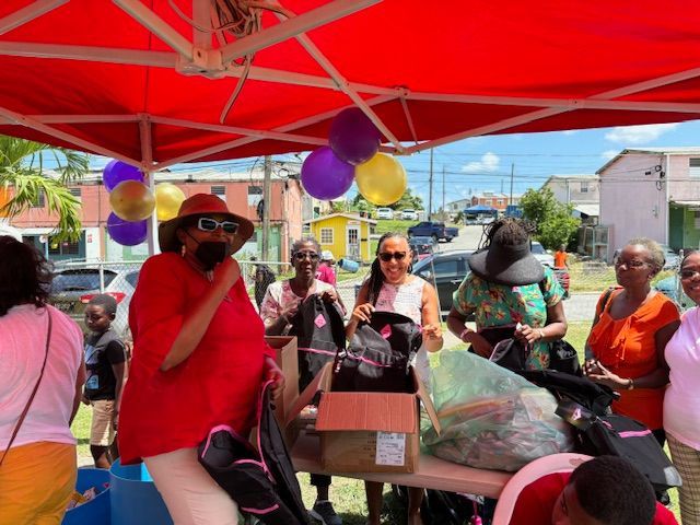 A group of people are standing under a red tent with balloons.