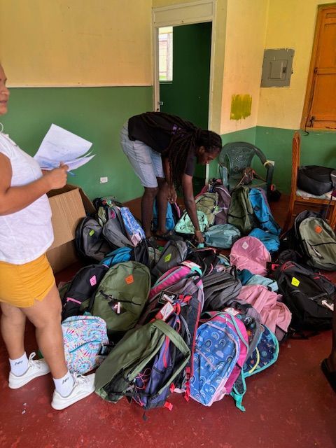 A man and a woman are standing in front of a pile of backpacks.