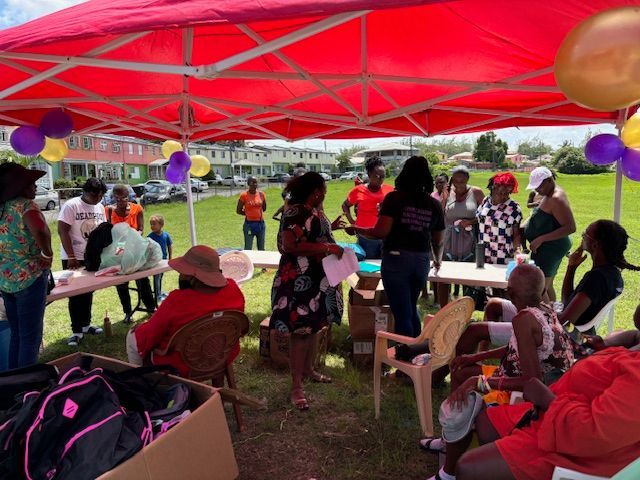 A group of people are gathered under a tent with balloons.