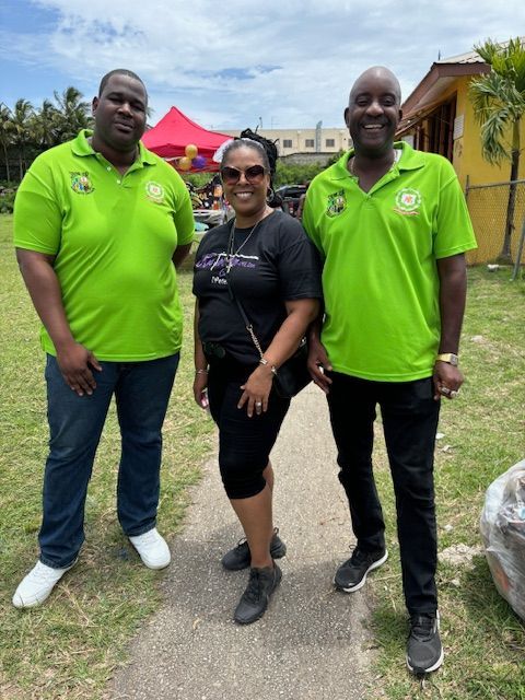 Three people wearing green shirts are posing for a picture