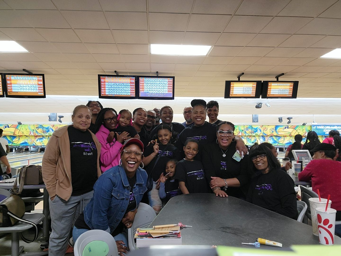 A group of people are posing for a picture in a bowling alley.