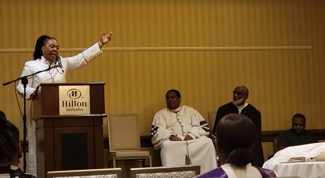 A woman is standing at a podium giving a speech to a group of people.