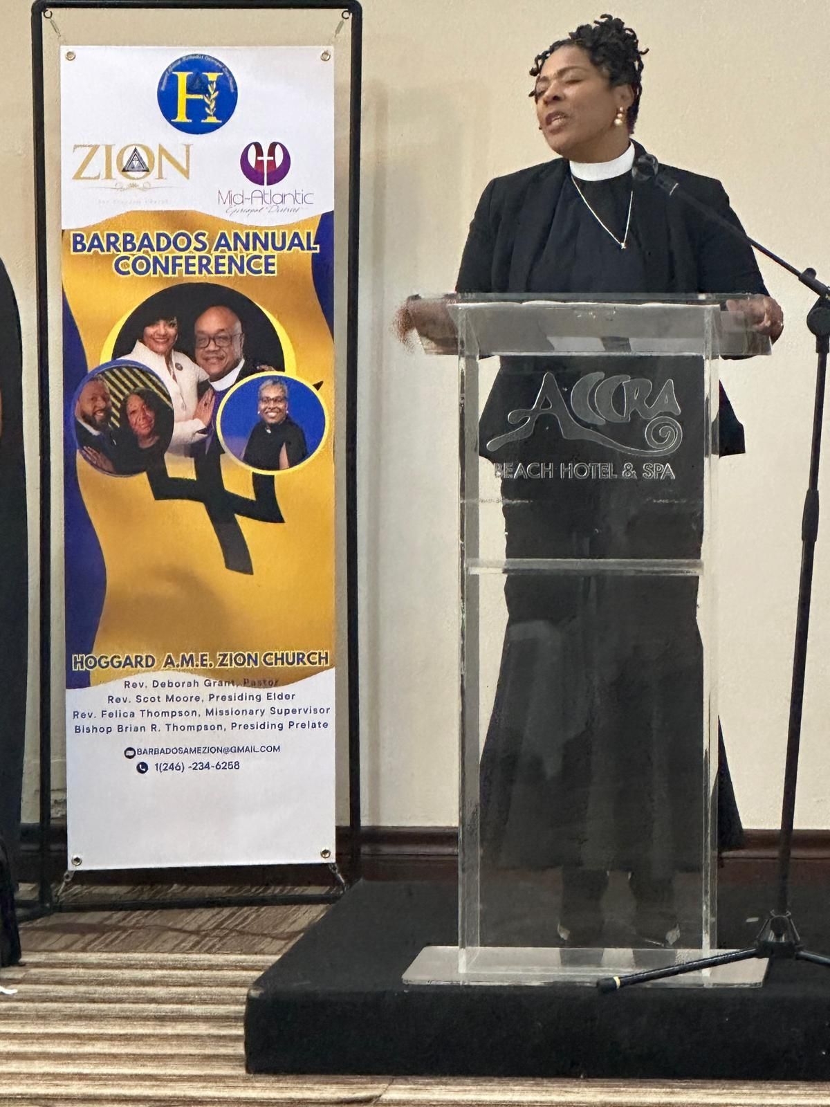 A woman is standing at a podium in front of a banner that says zion