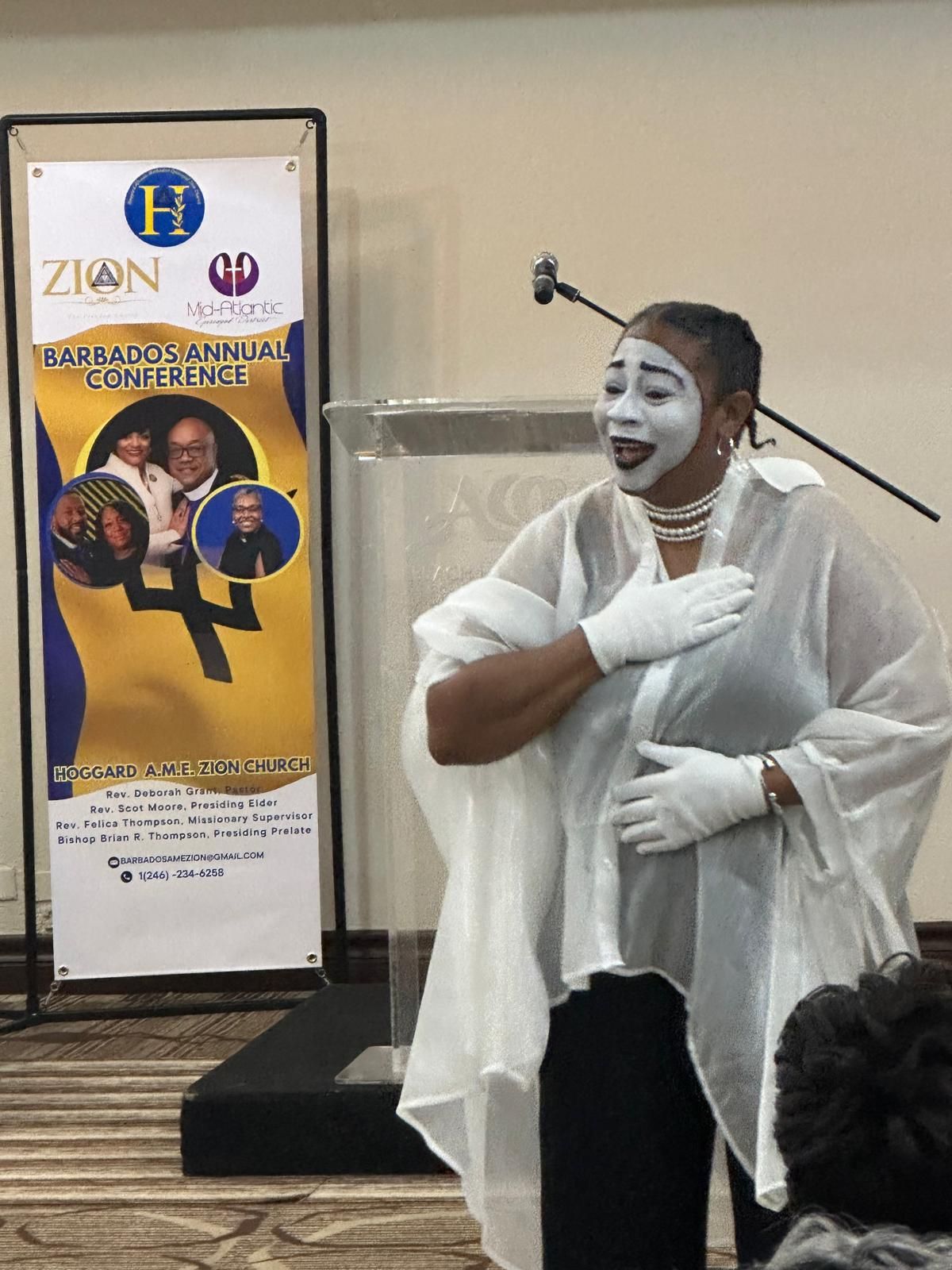 A woman with white paint on her face is standing in front of a podium.