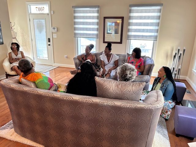 A group of women are sitting on a couch in a living room.