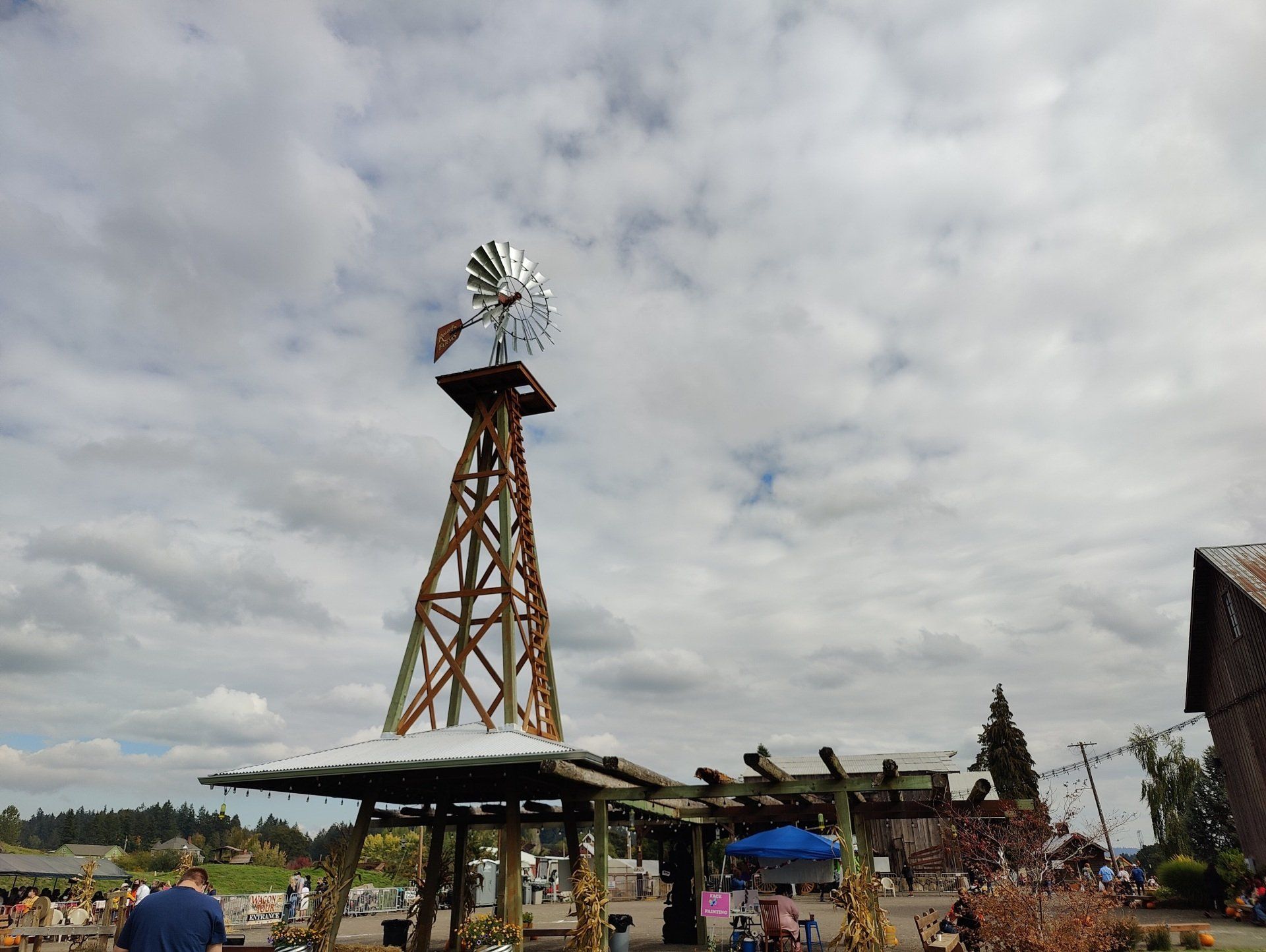 A large windmill is sitting on top of a wooden structure in a field.