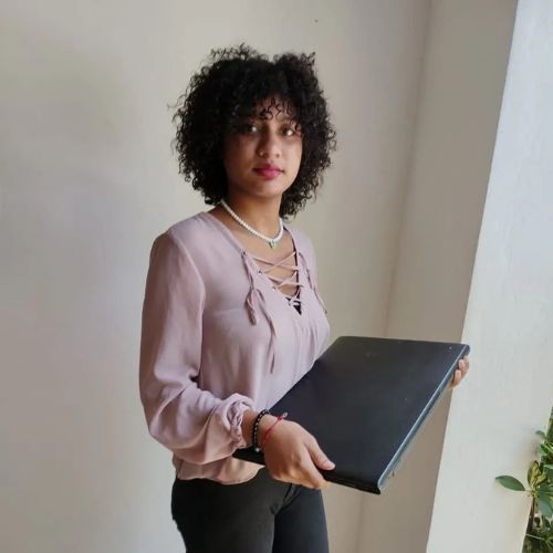 A woman with curly hair is holding a laptop in her hands.