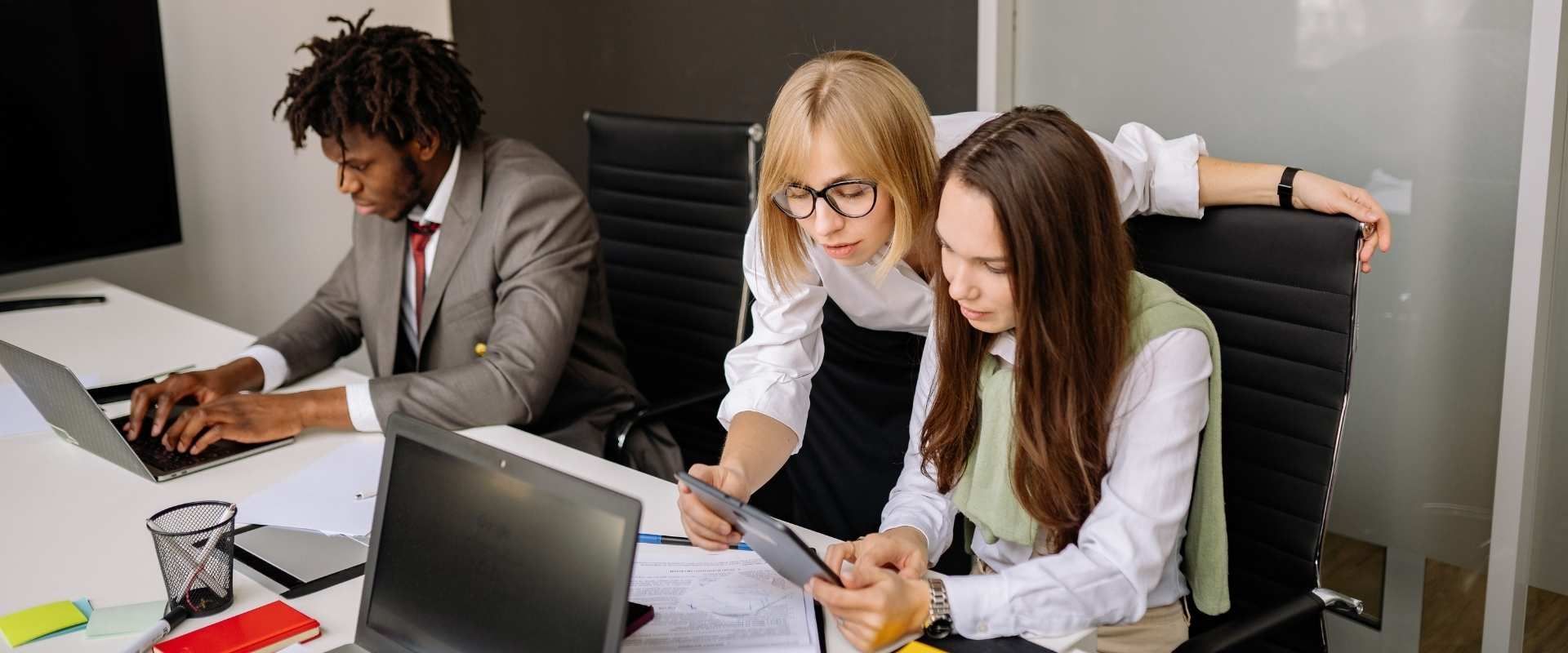 Three coworkers are reviewing documents at a conference table with a laptop and papers