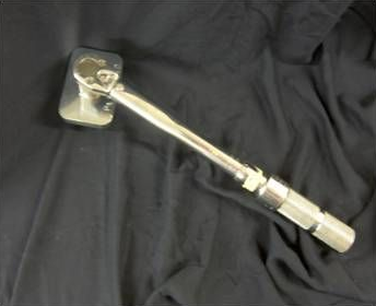 Silver ratchet wrench on a black fabric background.