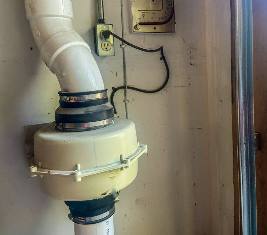 White dust collection system components attached to a wall with electrical wiring.