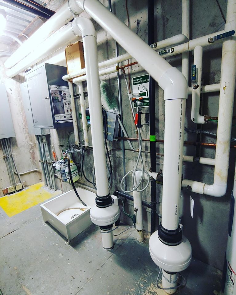 A temperature control device on a table in a dimly lit basement, surrounded by storage bins and laundry machines.