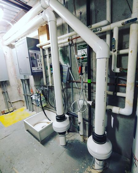 A temperature control device on a table in a dimly lit basement, surrounded by storage bins and laundry machines.