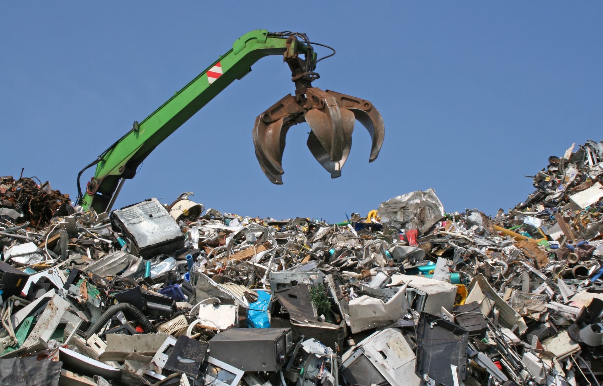 Crane sorting iron and electronics at a junkyard during recycling scrap metal operation. Crane sorting iron and electronics at a junkyard during recycling scrap metal operation.