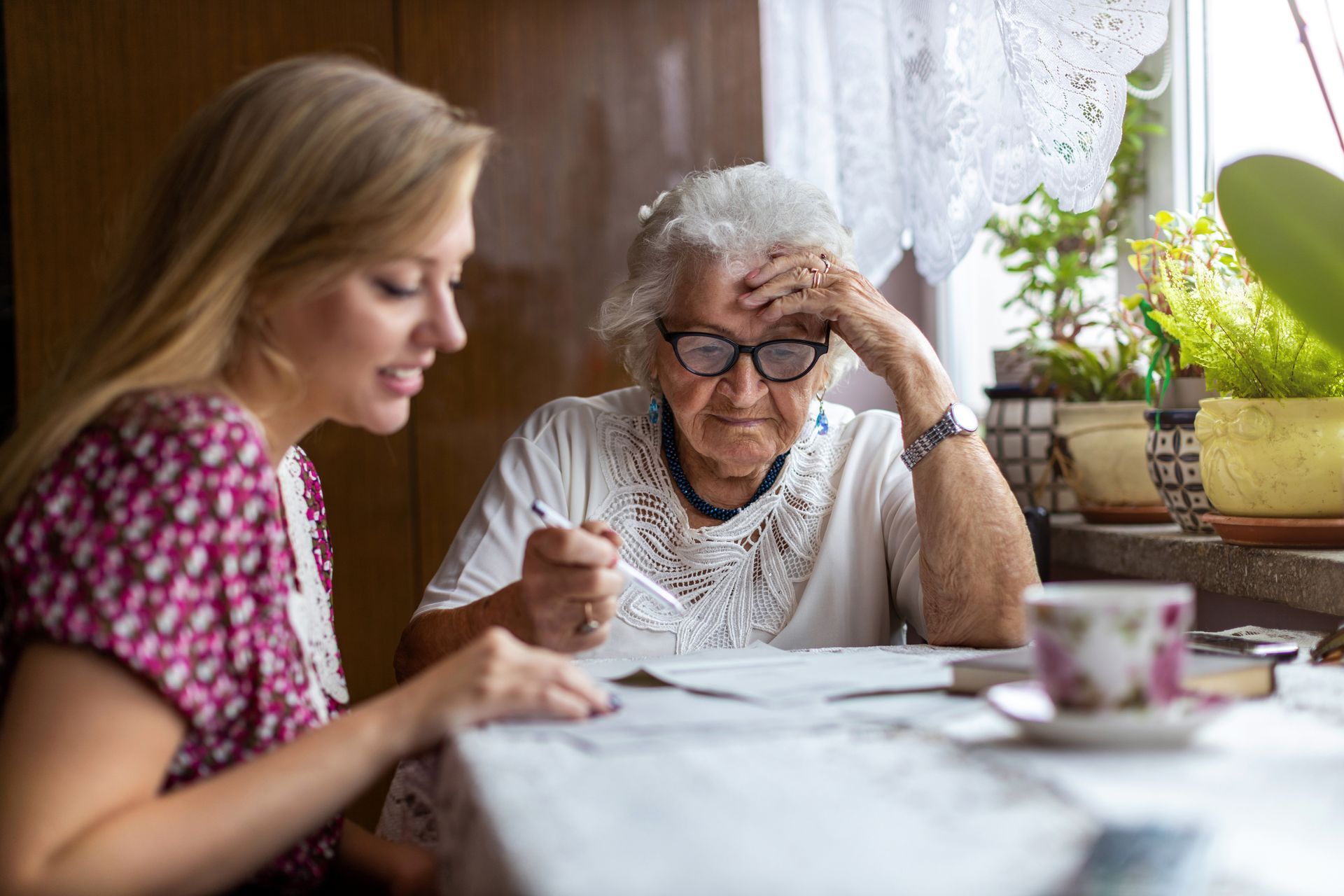 Caregiver with a group of seated seniors, smiling. Light-filled room with a window. Caregiver with a group of seated seniors, smiling. Light-filled room with a window.