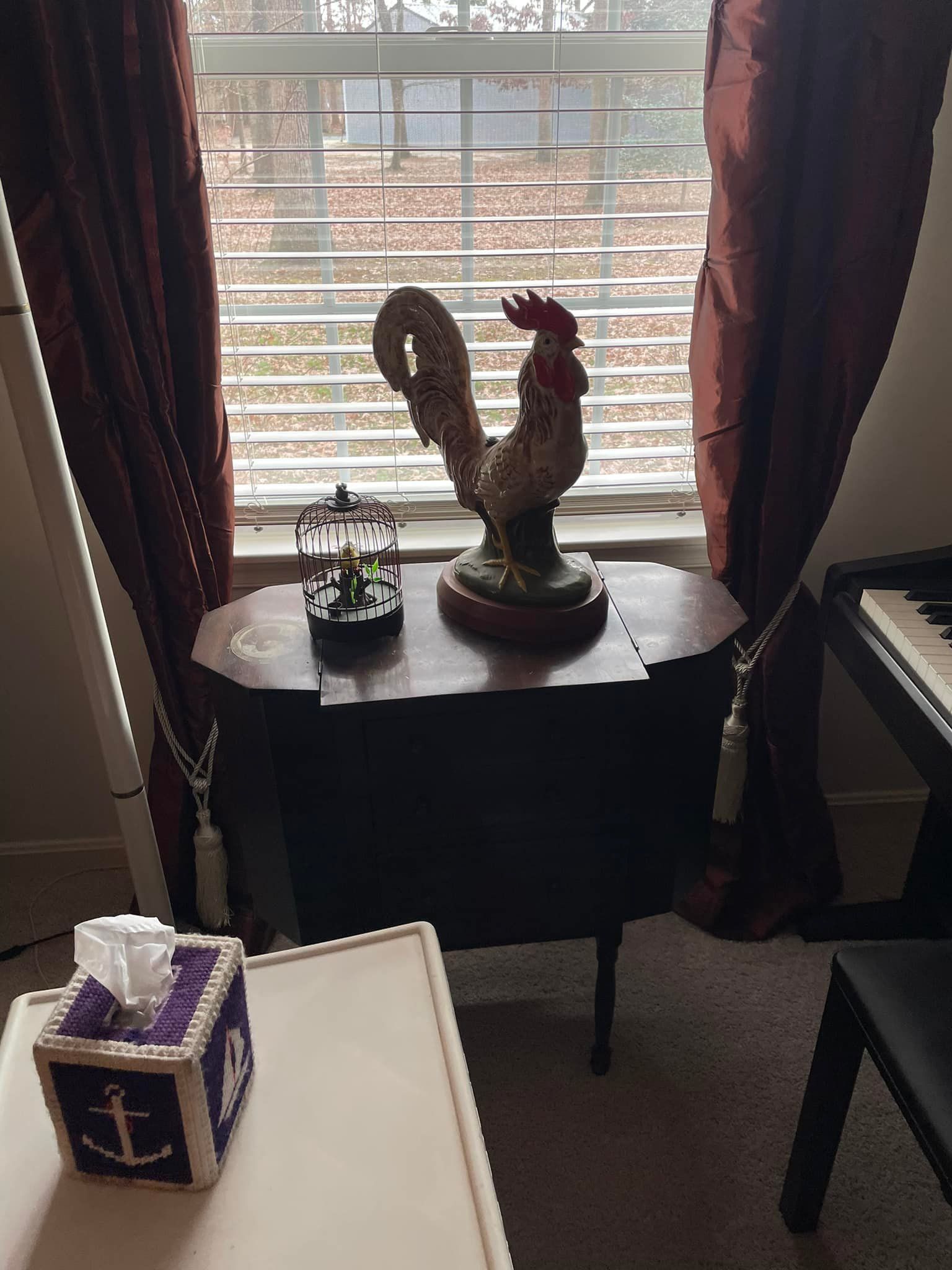 a statue of a rooster is sitting on a table in front of a window .