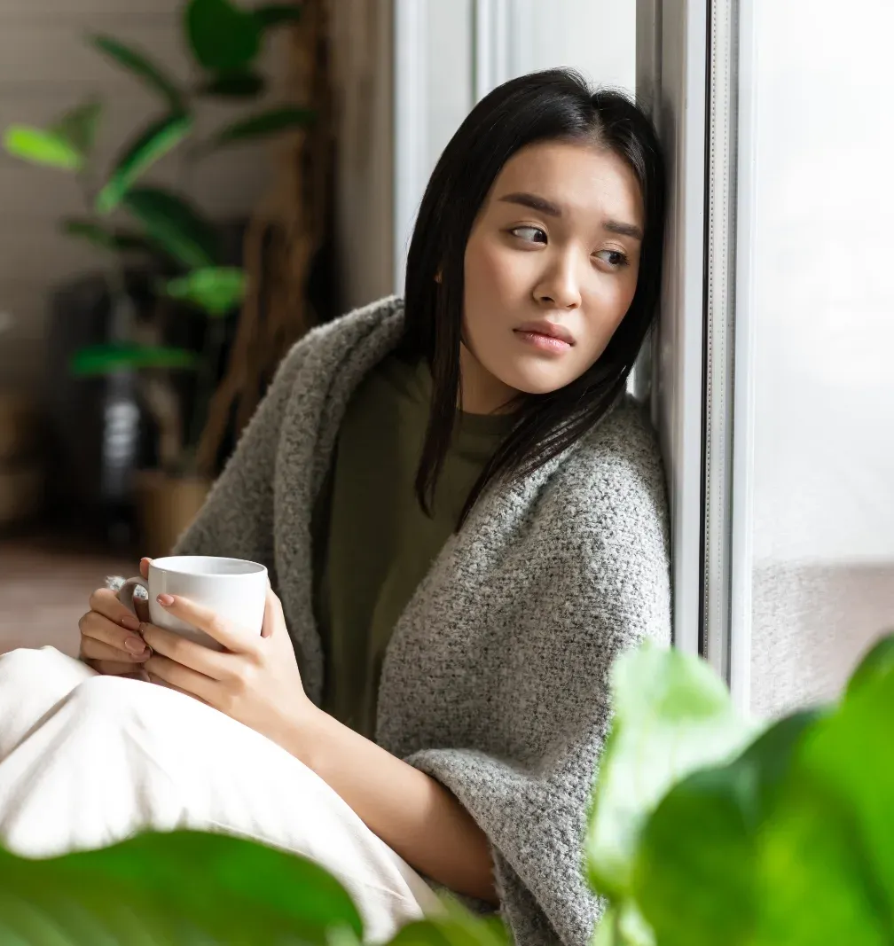 A lady sitting at a cafe with hands on her chest.