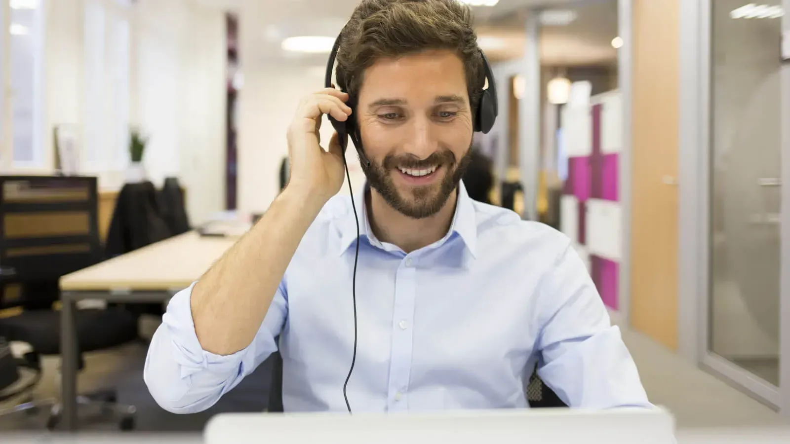 A man wearing headphones is sitting in front of a laptop computer.