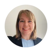 A woman in a blue shirt and black jacket is smiling in a circle.