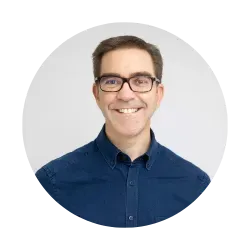 A man wearing glasses and a blue shirt is smiling in a circle.
