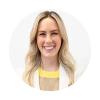 A woman in a white jacket and yellow sweater is smiling in a circle.
