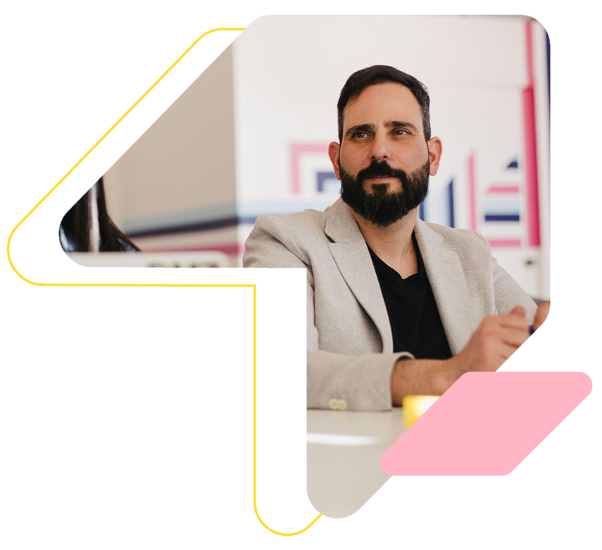 A man with a beard is sitting at a desk in front of a computer.