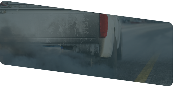 A white pickup truck driving on a road, kicking up a large cloud of dust behind it. | Diesel & Auto Performance