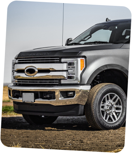 A gray Ford Super Duty pickup truck parked on a dirt lot, viewed from the front quarter angle. | Dierks Diesel & Auto Performance