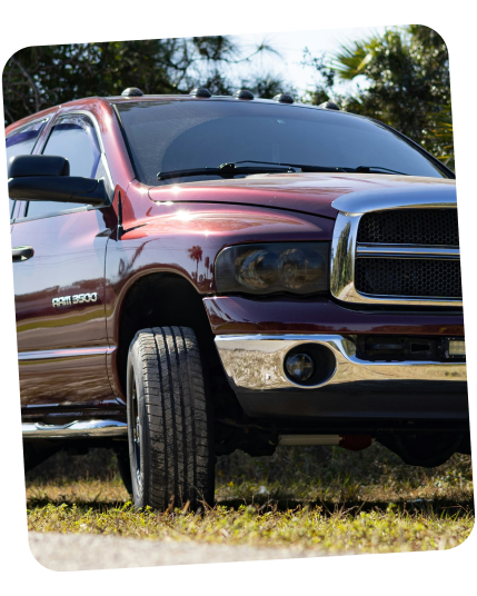 A maroon Dodge Ram 3500 pickup truck parked on a grassy field on a sunny day. | Dierks Diesel & Auto Performance