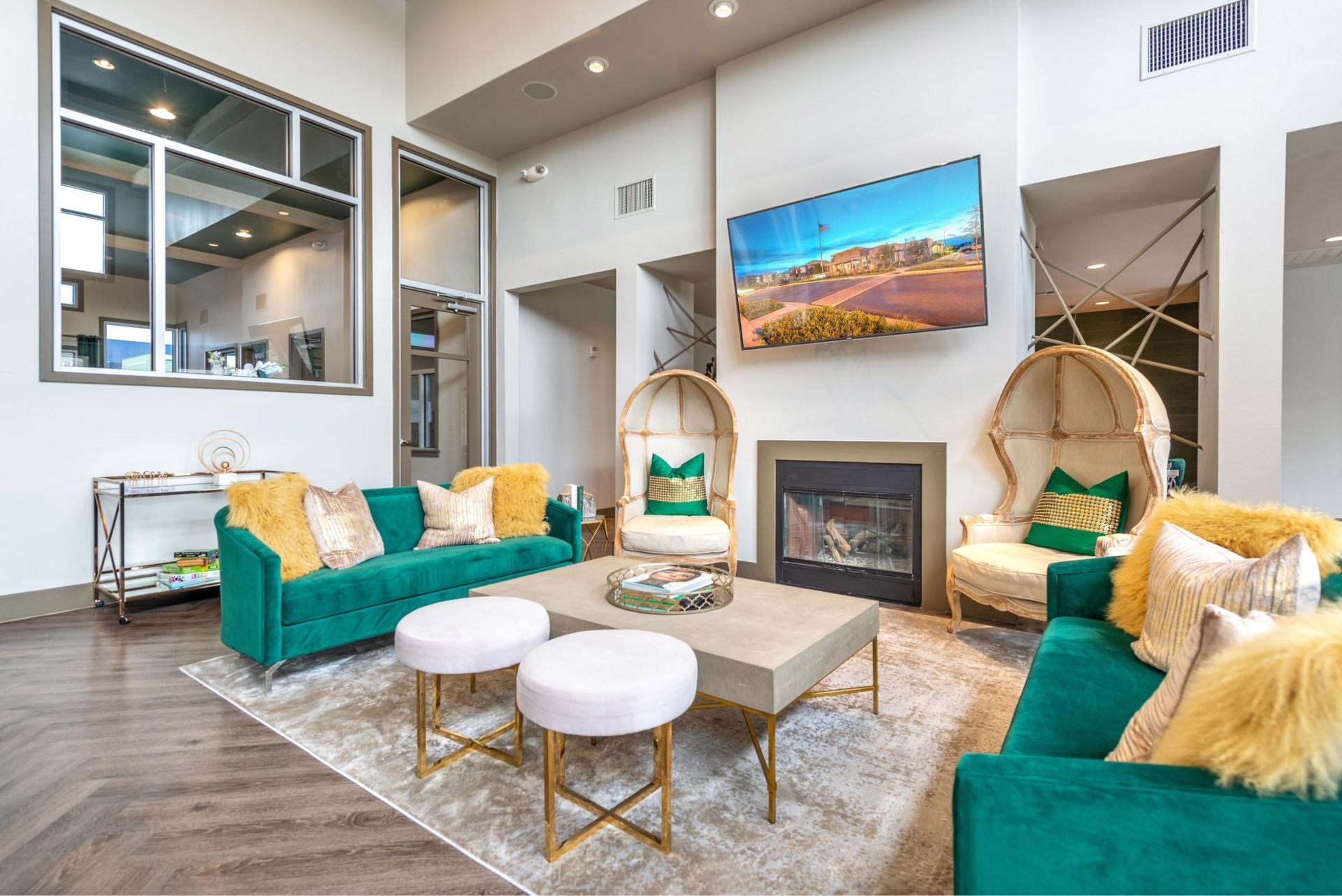 Modern community lounge with teal sofas, a fireplace, and a wall-mounted TV.
