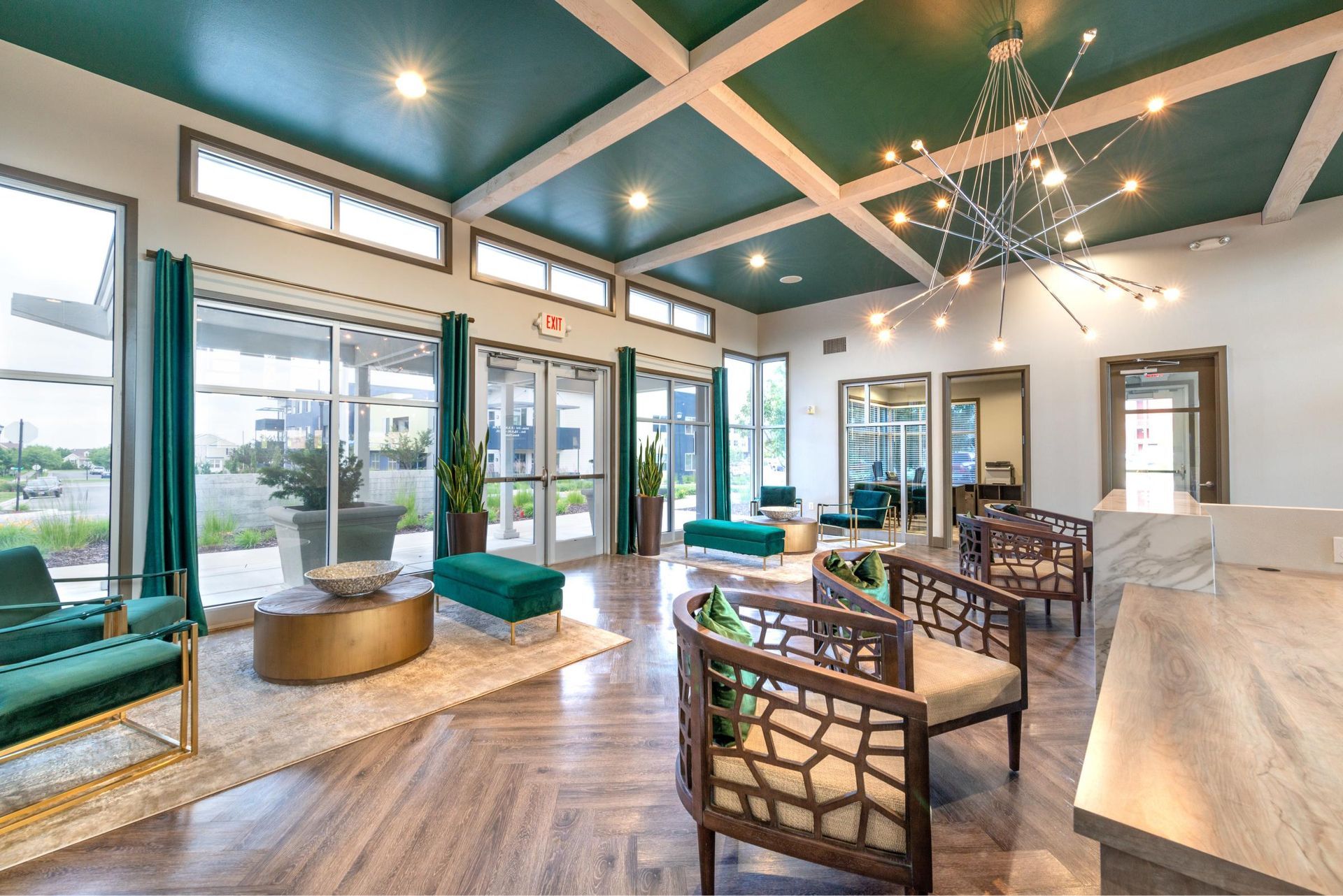 Bright modern apartment lobby with teal ceiling, large windows, and contemporary seating.