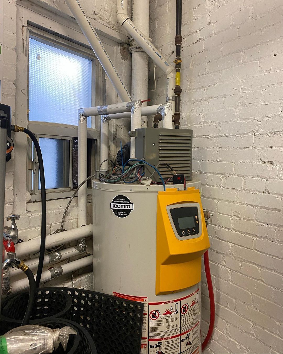 A water heater is sitting in a room next to a window.