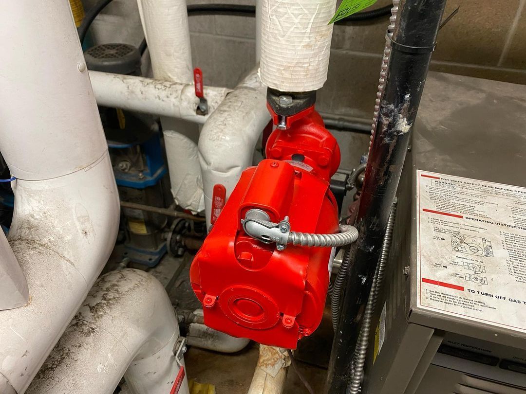 A red pump is connected to a white pipe in a room.