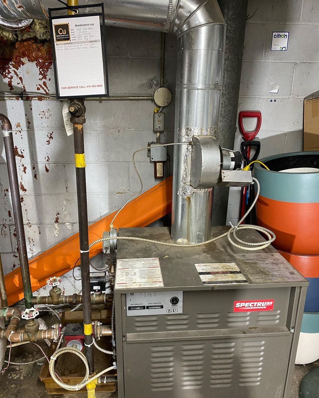 A boiler is sitting in a room next to a wall.