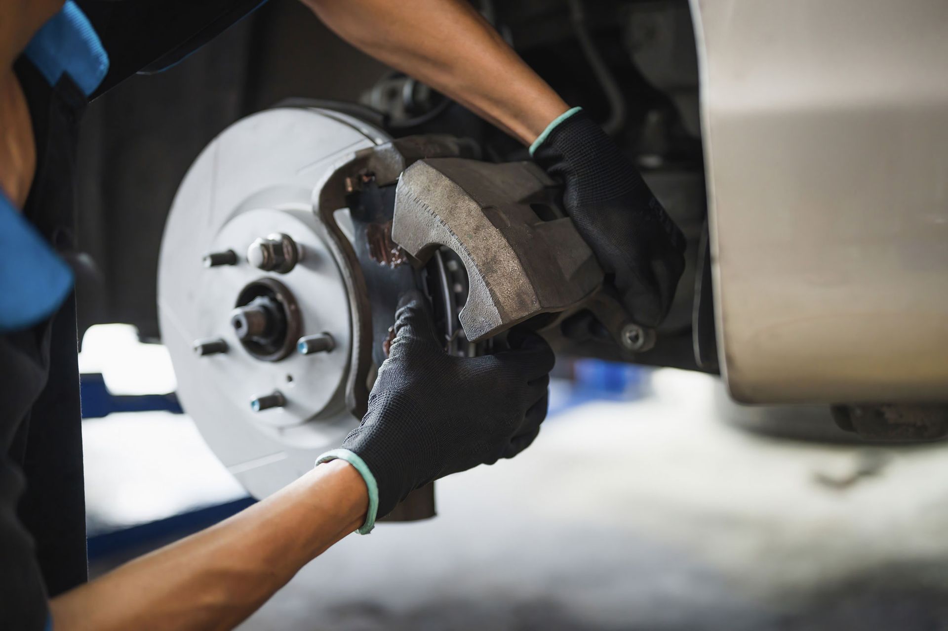 Mechanic replacing a car brake rotor with gloved hands