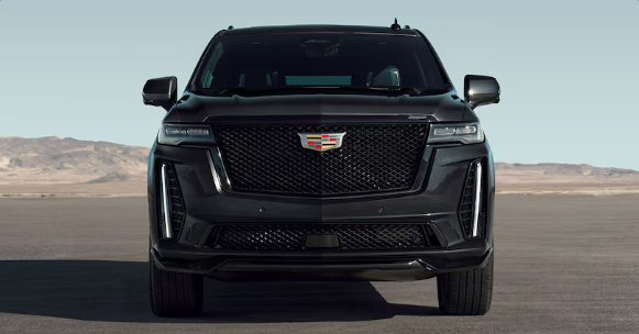 A black cadillac escalade is parked on a desert road.