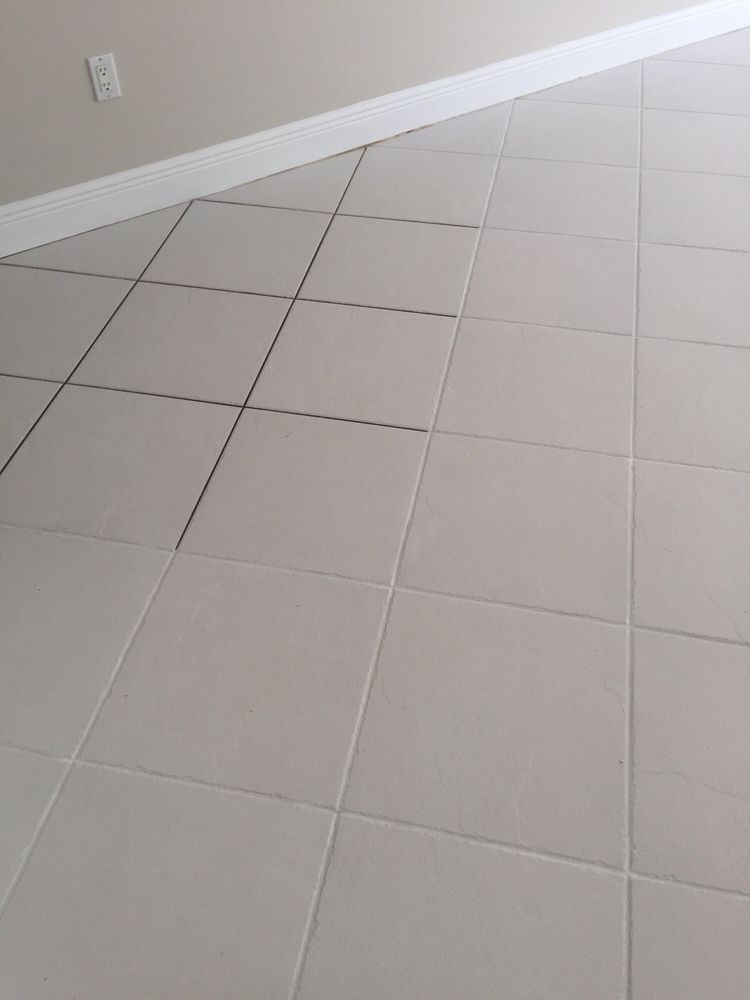 White tile floor in a room with a white baseboard.