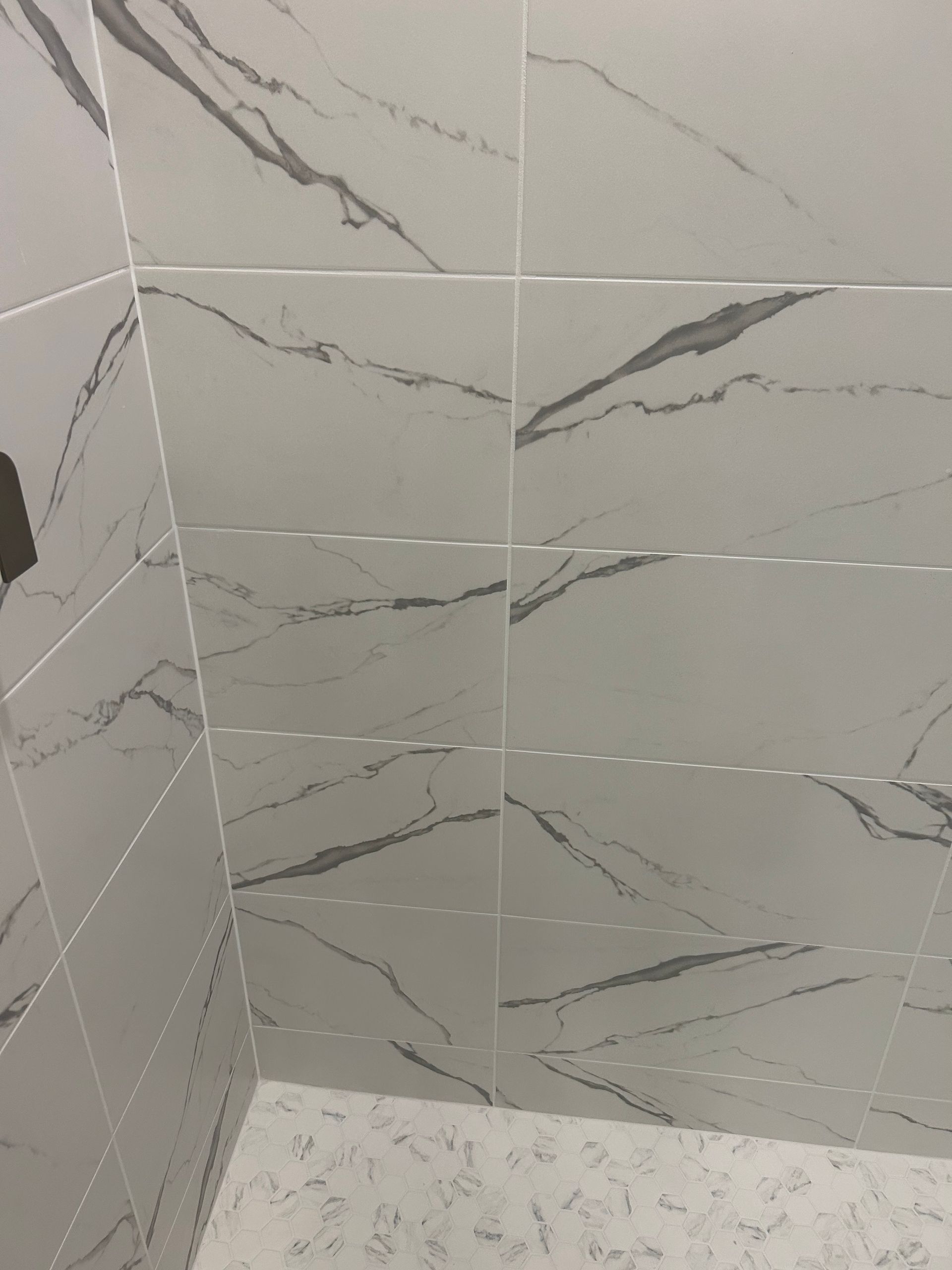 White tiled shower with gray veining, in a corner.